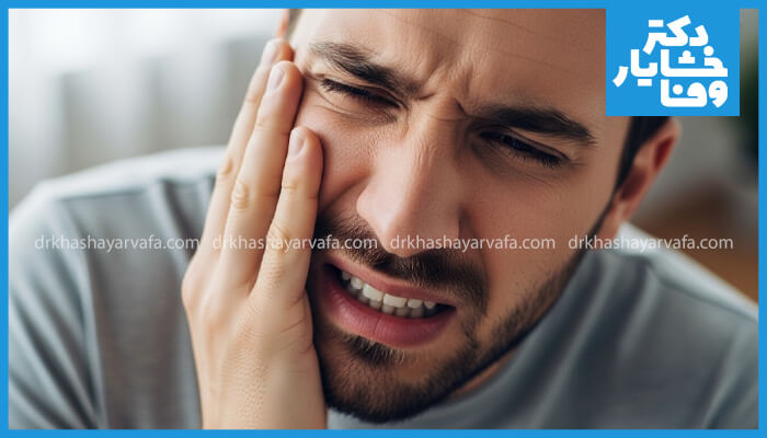 این تصویر مراقبتهای پس از جراحی دندان عقل را نشان میدهد. مردی روی کاناپه نشسته و برای کاهش تورم و درد، از کمپرس یخ روی گونهاش استفاده میکند. دارو و نوشیدنی نیز در کنار او قرار دارد.