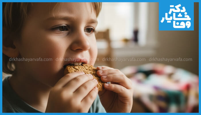  نمای نزدیک از کودکی که در حال خوردن بیسکویت است و به دلیل احتمالی دندان‌درد، یک سمت دهانش را برای جویدن ترجیح می‌دهد. این تصویر به علائم اولیه پوسیدگی دندان در کودکان اشاره دارد.