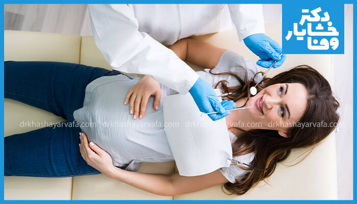 زن باردار در حال معاینه دندانپزشکی با دندانپزشک، خوشحال و آرام.