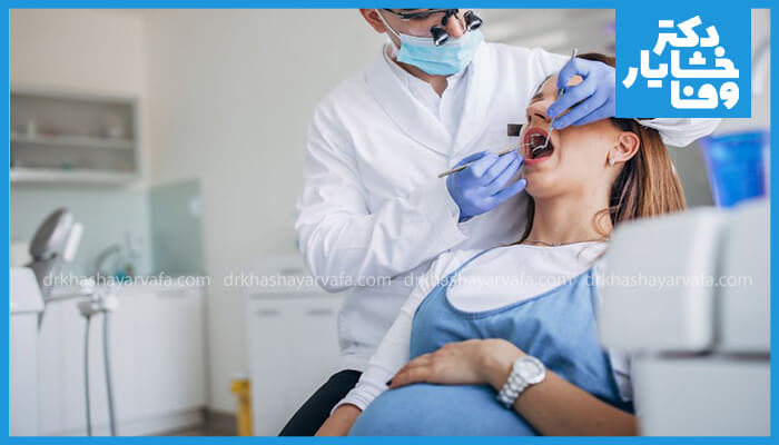  دندانپزشک در حال معاینه دندان زن باردار در مطب.